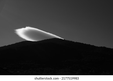 Black And White Image Of Clouds Over The Silhouette Of Mountain. Back Lit Image.