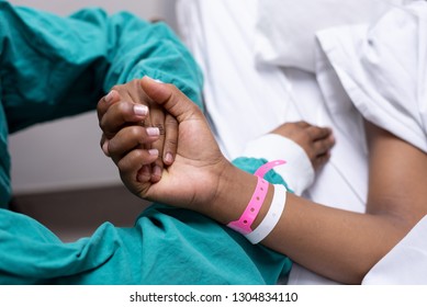 A black and white image of a doctor holding a patients hand - Powered by Shutterstock