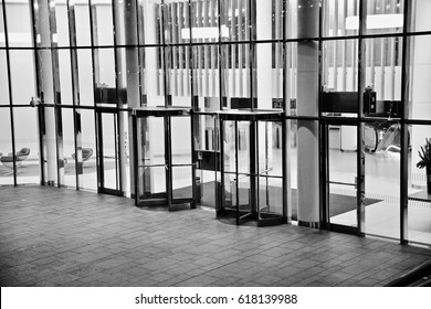 Black And White Image Of A Group Of Revolving Doors On A London Office Building.