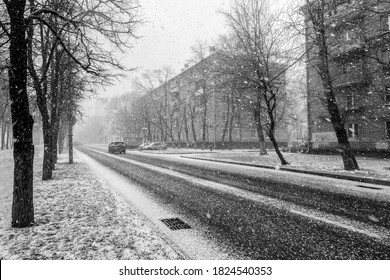 Black And White Image Of A Heavy Snowfall. View From The Car Window On The Road In The Snow. Snow Storm In The City.