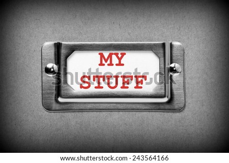 A black and white image of a metal drawer label holder with a white index card and the title My Stuff added in red text
