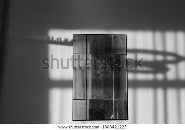 Black and white image of an old\
mirror with several separate sections hanging on the\
wall