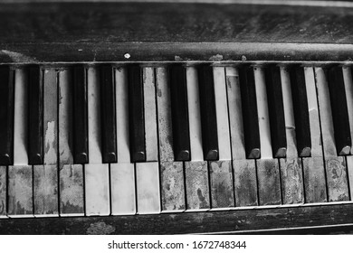 Black And White Image Of An Old Worn Out Piano. Old Key Board. Ancient Piano Background. 