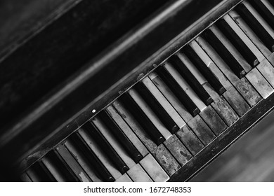 Black And White Image Of An Old Worn Out Piano. Old Key Board. Ancient Piano Background. 