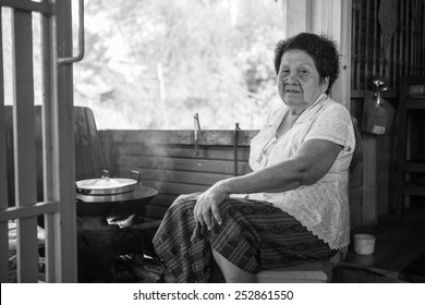 Black And White Image Of Senior Asian Woman Cooking In Kitchen