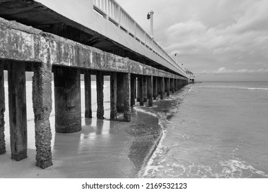 Black And White Image Of Side View Of Pier At The Beach At Sunset Time.Thailand.