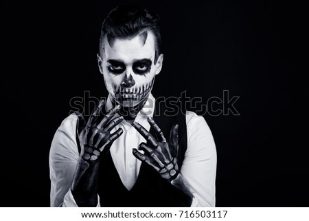 Black and white image of skull make up portrait of young man in studio.