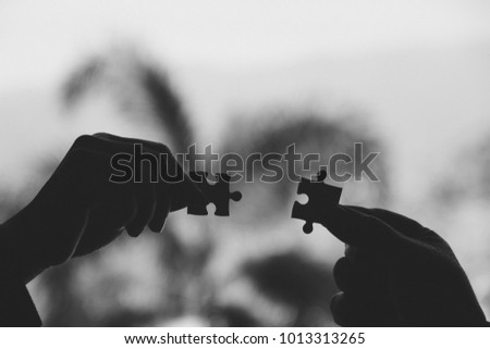 Black and white image of two hands holding a jigsaw puzzle with feeling love 