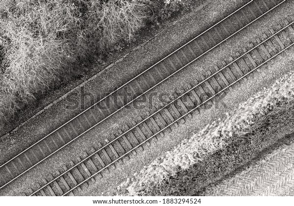 Black and white image of two railway tracks which\
consists of two parallel steel rails, anchored perpendicular to\
members called ties (sleepers) of concrete to maintain a consistent\
distance apart.