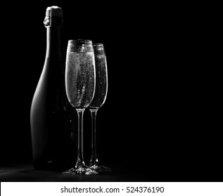 Black And White Image Of Two Wine Glasses With Champagne And A Bottle Of Champagne, The Outlines And Highlights, Black Background