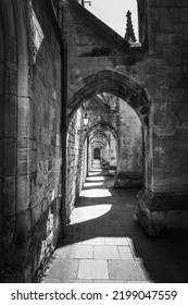 Black And White Image Of Walkway Through Church Cathedral Arch. Stone Building With Multiple Arches. 