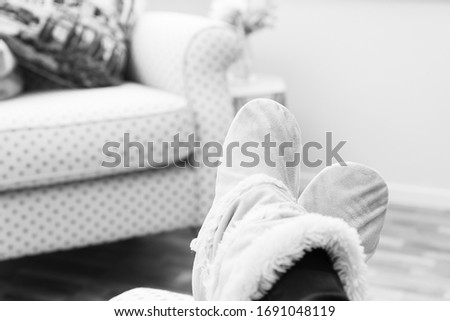 Black and white image woman's feet up in cosy slippers relaxing whilst staying at home during lock down