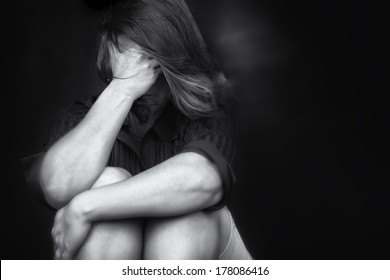 Black and white image of a young woman crying and covering her face useful to illustrate stress, depression or domestic violence - Shutterstock ID 178086416