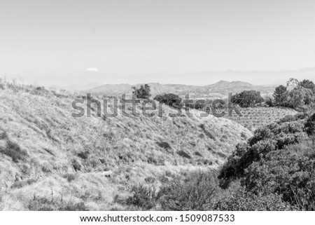 Black and white landscape of California mountains in dry late summer with city in distance