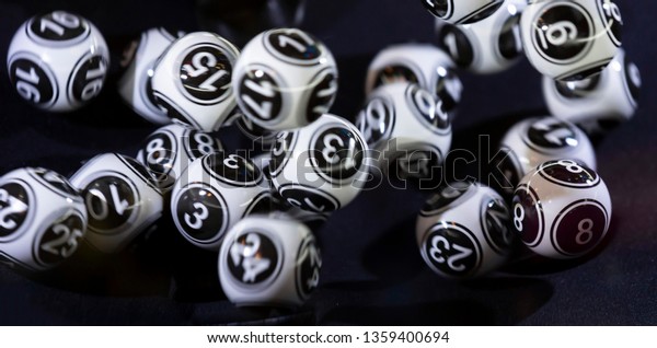 Black and white lottery balls\
in a bingo machine. Lottery balls in a sphere in motion. Gambling\
machine and euqipment. Blurred lottery balls in a lotto\
machine.