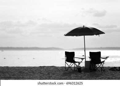 Black And White Of Lounges Chairs And Umbrella On The Beach In A