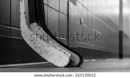 Black and white macro shot of hockey stick blades laid on a dirty arena floor - Shallow depth of field
