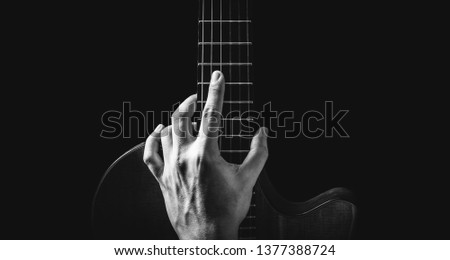 black and white male musician hand posing on guitar, isolated on black, music background 