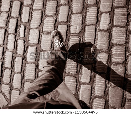 Black and white man feets POV walking on the cobblestone paved roads of Hamburg black and white
