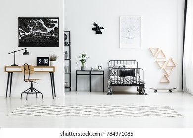 Black And White Map Posters Hanging Above Wooden Desk With Laptop And Metal Frame Bed