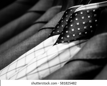 Black And White Of Men's Shirts And Suit Hanging On Rack.