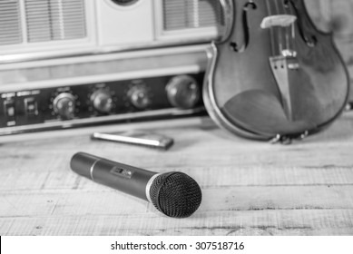 Black And White The Microphone Is Placed On Wood  Floor With  The Old Radio ,Violin , Mounth Organ  ,vintage Style Picture