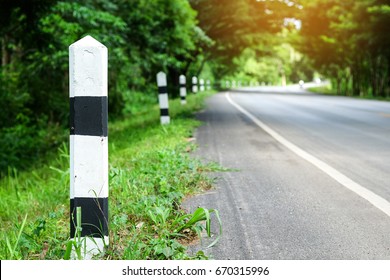 Black and white milestones with green grass roadside, Trees roadside in background . concept for next step.
