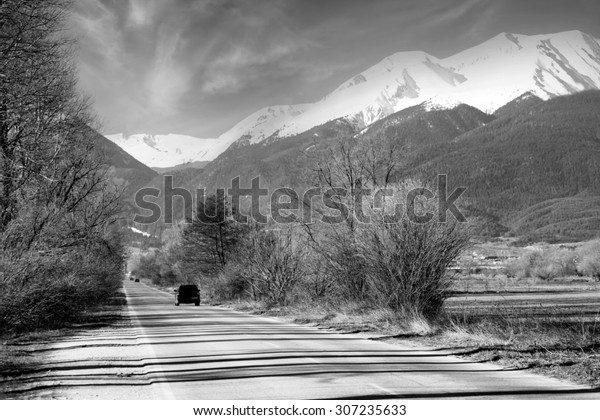 black and white\
mountain road and high peak covered with snow, Bansko ski resort in\
bulgarian Pirin mountains