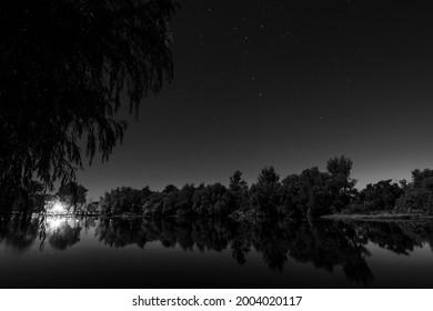 Black And White Night Shot Of A Tranquil River Mirroring The Trees And Stars In The Sky Showing The Southern Cross In Villa Paranacito, Entre Ríos, Argentina