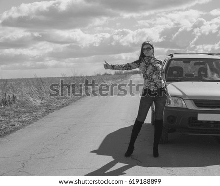 black and white, outside the city, raising the thumb a beautiful girl stops the car.