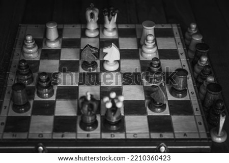 Black and white overhead shot of a wooden chess board with some pieces on it
