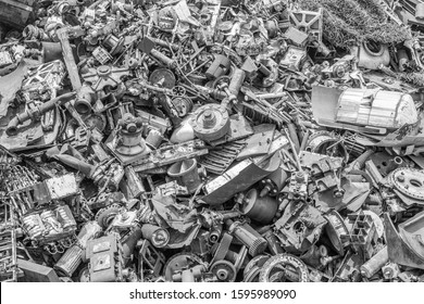 A black and white, overhead view photo of a giant pile of industrial scrap metal and used machine parts of all shapes and sizes.