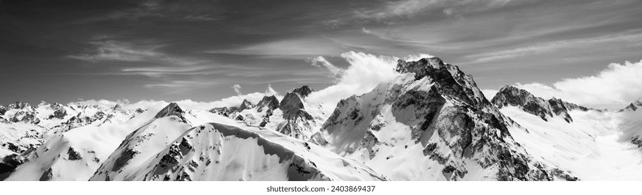 Black and white panorama of high snow-capped mountain peaks and beautiful sky with clouds at sun windy day. Caucasus Mountains in winter, region Dombay, mount Dombay-Ulgen. - Powered by Shutterstock