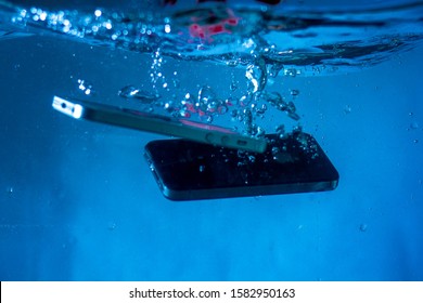black and white phone dropped into the water. phone in water.phone in water bubbles.phone sinks in water