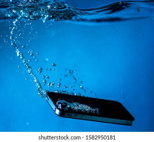 black and white phone dropped into the water. phone in water.phone in water bubbles.phone sinks in water