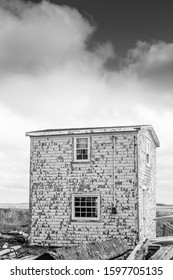 A Black And White Photo Of An Abandoned Cottage House With Peeling White Paint On The Atlantic Coast Under Storm Clouds.