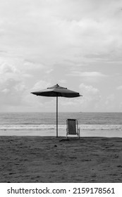 Black And White Photo Of A Beach Umbrella And A Chair On A Deserted Beach With No People