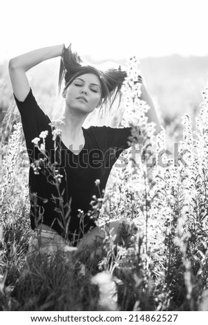 Beautiful young photographer woman wearing black clothes, sitting on the floor in countryside with her camera