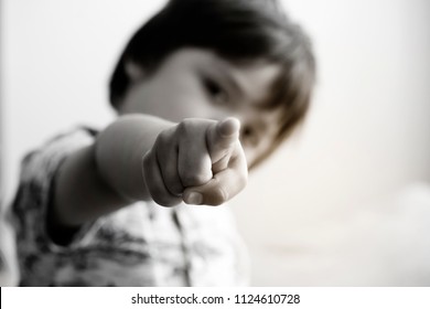 Black And White Photo Blurry Face Of Little Boy Finger Pointing At Camera, Selective Focus Of Kid Primary School Boy Pointing At You With His Finger, Spoiled Children Concept