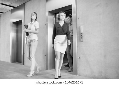 Black And White Photo Of Business People Coming Out Of Elevator In Office