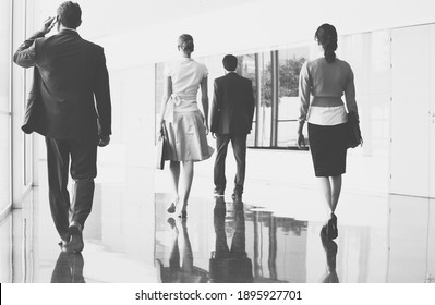 Black And White Photo Of Business People Walking On Marble Flooring In Office