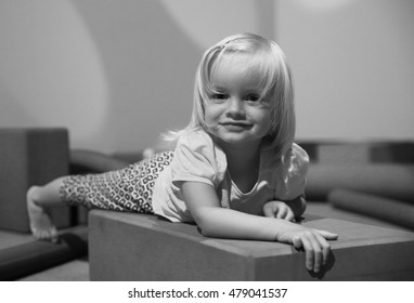 Black And White Photo Of Cute Little Girl Lying On Floor In Playing Room. New Plymouth, NZ