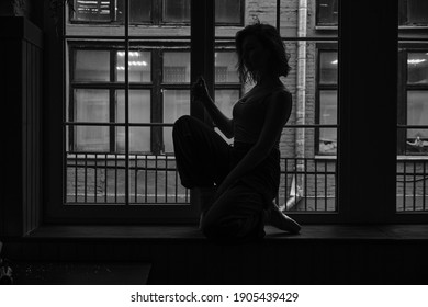 Black And White Photo Of Dancer In The Window Frame In An Old Building. Young, Elegant, Graceful Woman Ballet Dancer