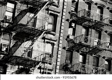 Black and white photo of the exterior of a building in New York with old fire escape. - Powered by Shutterstock