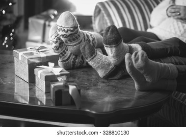 Black And White Photo Of Family Warming Feet At Fireplace