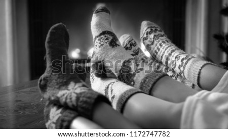 Black and white photo of family wearing knitted woolen socks relaxing by the fireplace