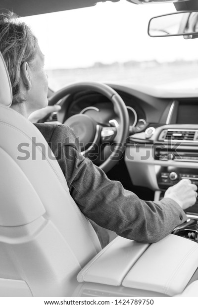 Black and White photo of Female executive driving\
car during business trip