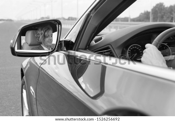 Black and white photo of Female executive driving\
car during business trip