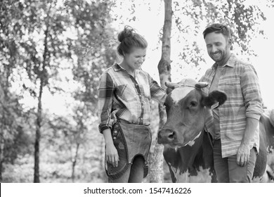 Black And White Photo Of Female And Male Farmer Petting Cow In Farm