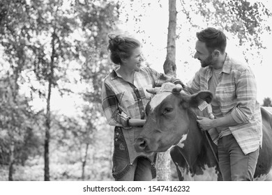 Black And White Photo Of Female And Male Farmer Petting Cow In Farm